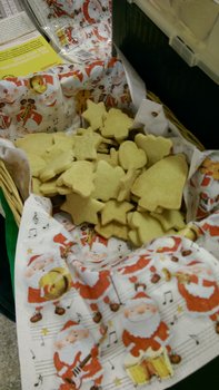 Auf dem Foto sind Plätzchen verschiedener Formen in einem Korb zu sehen. Zwischen den Plätzchen und dem Korb sind Servietten mit Weihnachtsmannmotiven.