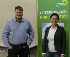 Monika Heinold und Marc Muckelberg stehen gemeinsam vor einem Aufsteller des Ortsverbandes Norderstedt